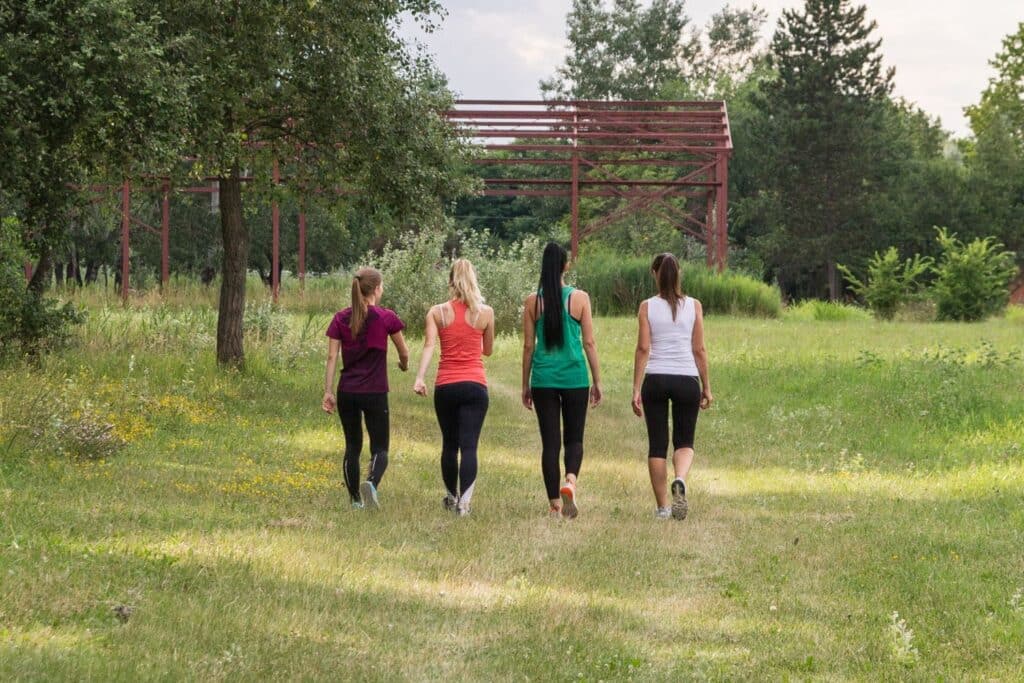 Un groupe de 4 femmes marchent dans la verdure en tenue de sport afin d'illustrer l'article maigrir en marchant mode d'emploi.