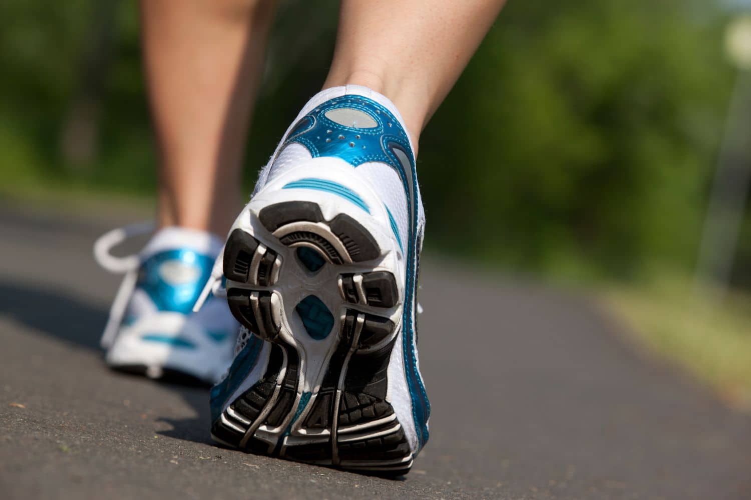 Des pieds d'un adultes qui porte des baskets bleues et blanches sont représentées sur la photo afin d'illustrer l'article maigrir en marchant mode d'emploi