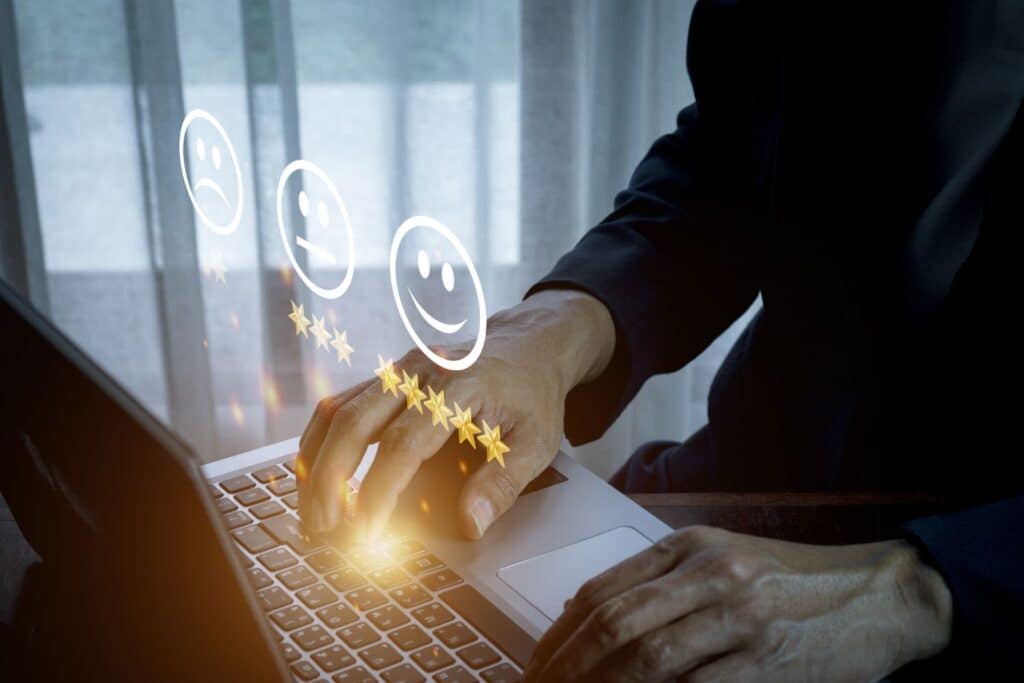 Des mains tapent sur le clavier d'un ordinateur avec des émoticônes illuminés au dessus pour illustrer l'article Est-ce que Swagbucks est fiable ? Découvrez toute la vérité