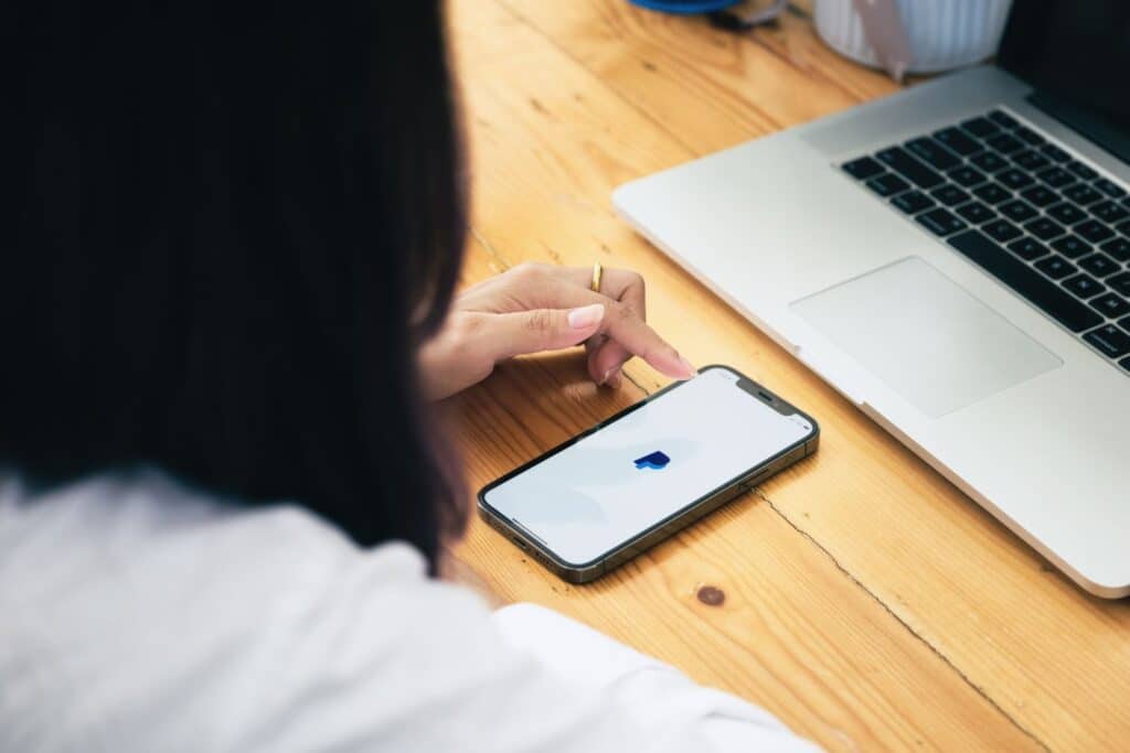 Une personne regarde son téléphone sur lequel est affiché l'icône Paypal pour illustrer l'article Est-ce que Swagbucks est fiable ? Découvrez toute la véritér le clavier d'un ordinateur avec des emoticone illuminés au dessus pour illustrer l'article Est-ce que Swagbucks est fiable ? Découvrez toute la vérité