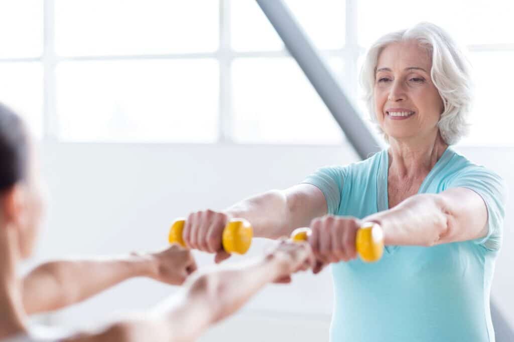 une femme âgée qui fait de la musculation dans le cadre du sport pour personne âgée à la maison